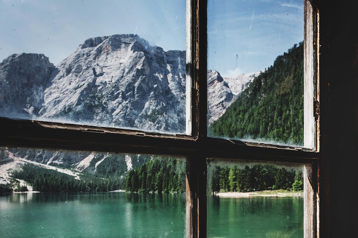 Blick durch ein Fenster auf Berge und einen Bergsee